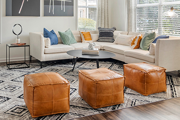 Tan and white living area with sectional and orange leather ottomans