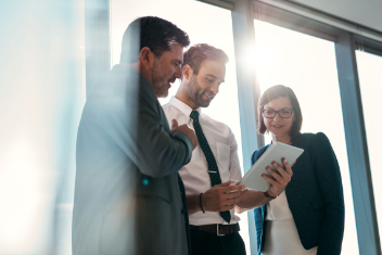 3 businesss professionals gather around a tablet