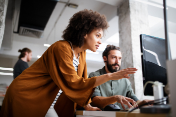 A man and woman work together on a computer 