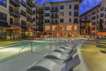 Lounge chairs line a luxury apartment pool at dusk