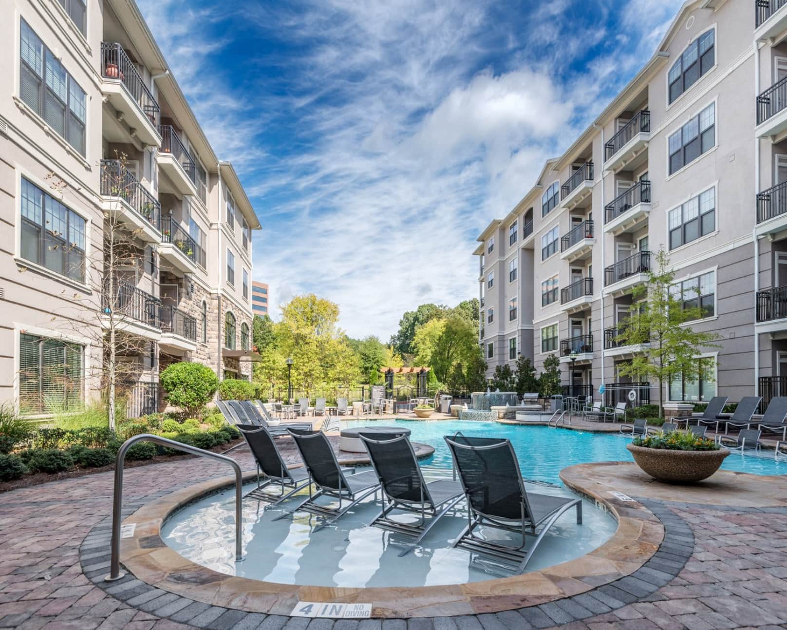 4 folding chairs in shallow end of pool surrounded by apartments