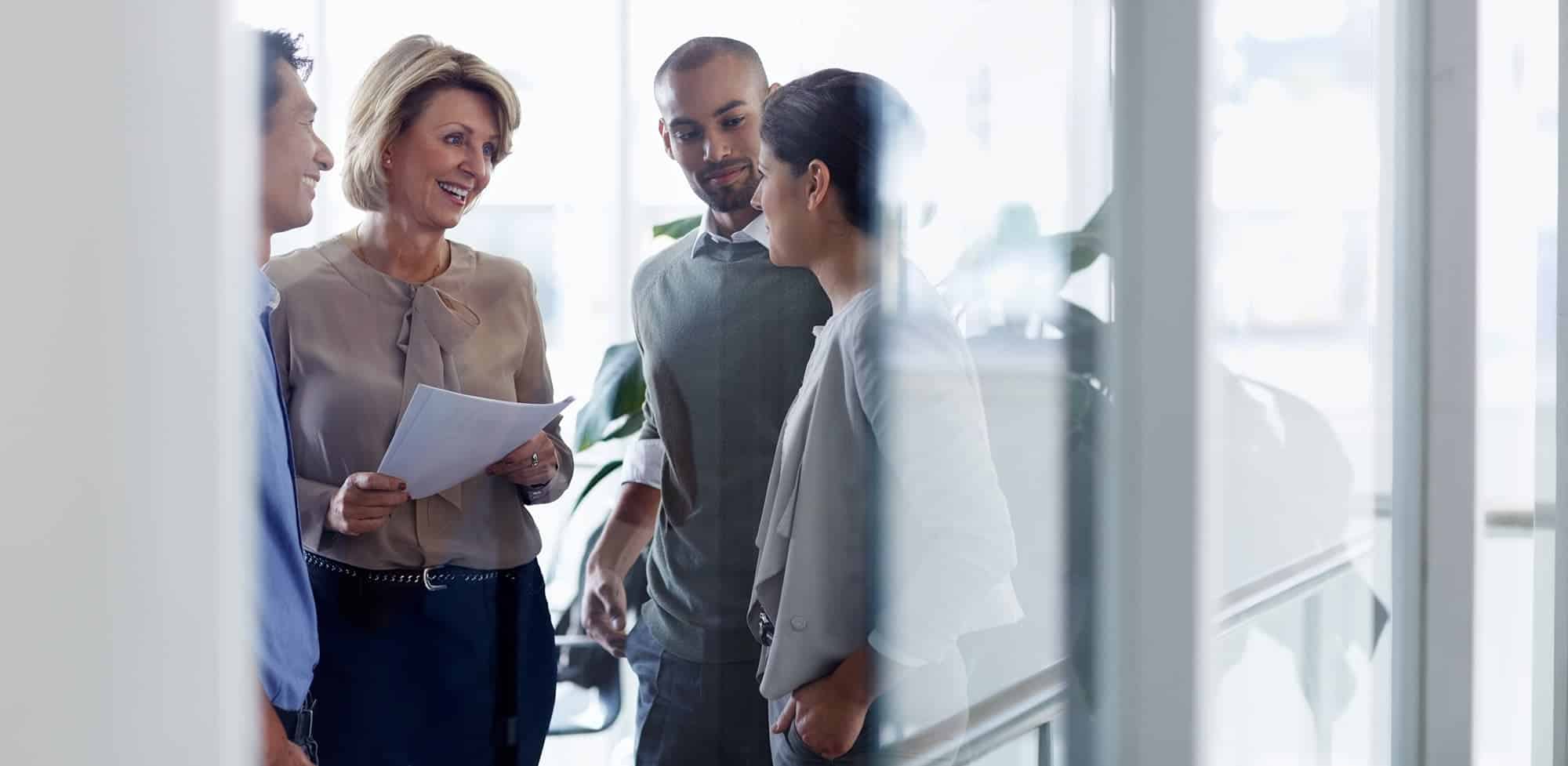 4 working professionals stand together and talk