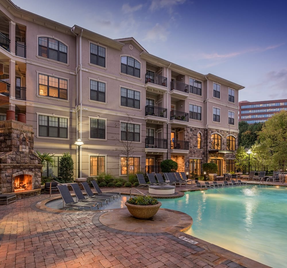 4-story tan and brick apartment building overlooking the pool