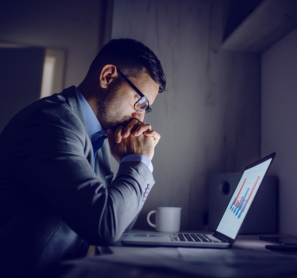 Businessman with glasses looks at a laptop